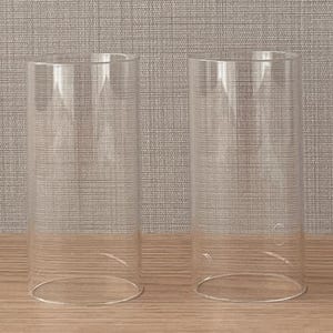 May include: Two clear, cylindrical glass shades with open tops and bottoms. These transparent glass tubes feature smooth, straight walls and a uniform design, providing a simple and functional structure for lighting fixtures or decorative display purposes.