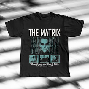Może przedstawiać: Czarna koszulka z białym napisem "THE MATRIX". Koszulka ma grafikę osoby w okularach przeciwsłonecznych na tle kodu binarnego. Poniżej znajdują się trzy mniejsze obrazy i cytat.