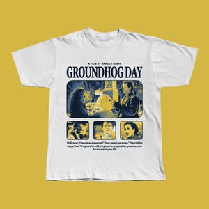 Könnte beinhalten: Weißes T-Shirt mit einem Filmposter-Design für "Und täglich grüßt das Murmeltier". Das Design enthält den Filmtitel, den Namen des Regisseurs und Szenen aus dem Film. Das T-Shirt hat auch ein Zitat aus dem Film.