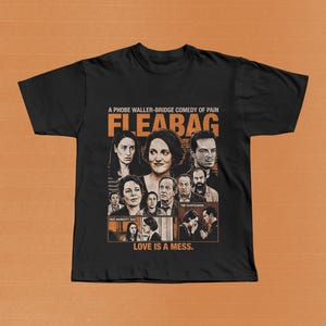 May include: Black t-shirt featuring a collage of images from the show "Fleabag." The design includes the show's title and the phrase "A Phoebe Waller-Bridge Comedy of Pain." Additional text reads "Her Haircuty Bad," "The Confession," and "Love is a Mess."