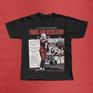 以下が含まれることがあります： 黒色のParks and Recreation Tシャツ。レスリー・ノープがTo-Doリストを指し示しています。リストには、Galentine's Dayの計画やロンに野菜を食べさせることなどが含まれています。シャツには他のキャラクターの画像と「Don't be a 'J' word. (A Jerk)」という引用句も含まれています。