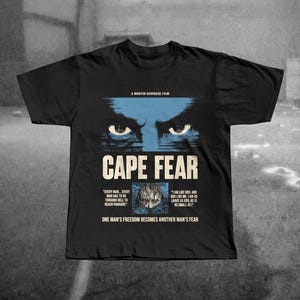 May include: Black t-shirt featuring the movie title "CAPE FEAR" in white font, with blue eyes graphic above. The text "A MARTIN SCORSESE FILM" is above the title. Quotes from the film are below the title.