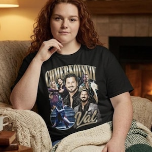 May include: A black short-sleeved t-shirt featuring a graphic print of Val Chmerkovskiy. The design includes multiple portraits of the dancer, a circular image of a couple performing a dance, and the text "CHMERKOVSKIY" and "Val" in gold lettering.