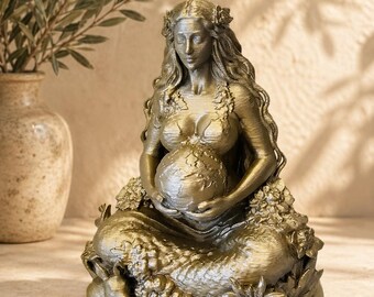 Puede incluir: Estatua dorada de una mujer sentada sosteniendo un globo terráqueo. La estatua tiene cabello largo y ondulado, detalles florales y está rodeada de flores, frutas y un conejo. Es un objeto decorativo.