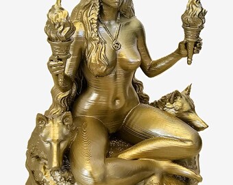 Puede incluir: Estatua dorada de una mujer sentada con pelo largo, sosteniendo antorchas. Está adornada con una luna creciente y un colgante. Un lobo descansa a su lado. La estatua está sobre una base texturizada.