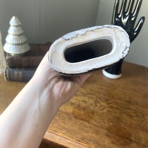 May include: A black ceramic hand with a white interior. The hand is holding a black and white ceramic arm. The arm has a white interior and the text "COMEX" is visible on the bottom.