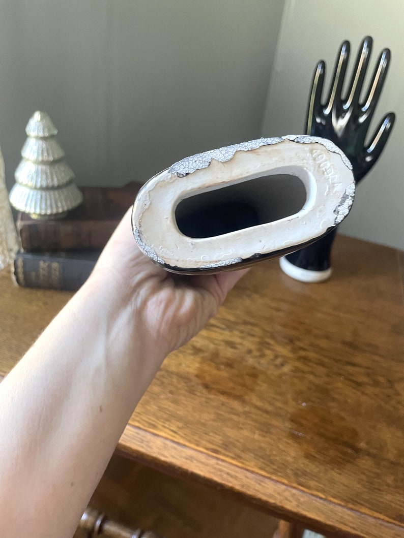 May include: A black ceramic hand with a white interior. The hand is holding a black and white ceramic arm. The arm has a white interior and the text "COMEX" is visible on the bottom.