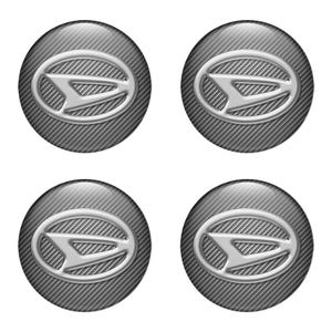 May include: Four Daihatsu car emblem center caps. Each cap is a silver oval with a carbon fiber-like background. The Daihatsu logo is in the center of each cap, a stylized silver "D" shape within a silver oval.