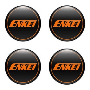 May include: Four black circular emblems with the word "ENKEI" in orange block letters. Each emblem has an orange border. The emblems are glossy and appear to be made of plastic or metal.