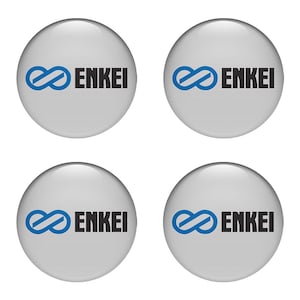 May include: Four circular, glossy, gray badges with the word "ENKEI" in black, and a blue infinity symbol logo. The badges are evenly spaced against a white background.