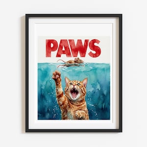 May include: Framed watercolor print featuring a ginger tabby cat reaching out of blue water towards a mouse. The word "PAWS" is written in red above the water, mimicking the "JAWS" movie logo. The cat has an open mouth and is reaching with its paw.