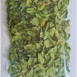 Puede incluir: Una bolsa de plástico transparente llena de hojas verdes secas. Las hojas tienen varias formas y tamaños, algunas muestran signos de coloración marrón. La bolsa está sellada y el contenido está densamente empaquetado.
