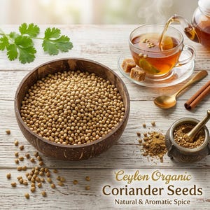 May include: A dark brown coconut shell bowl filled with light brown coriander seeds. Nearby is a glass cup of tea with a lime slice, a gold spoon, cinnamon sticks, a mortar and pestle with ground spice, and green leaves. Text reads: Ceylon Organic Coriander Seeds Natural & Aromatic Spice.