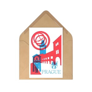 Peut inclure: Une carte postale avec un graphisme rouge et bleu de l'architecture de Prague, comprenant une tour et des arches, avec le nom de la ville en bleu. La carte postale est dans une enveloppe marron.