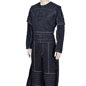 May include: A dark navy blue jumpsuit with white stitching. The long-sleeved top has a logo, and the trousers have cargo pockets and knee padding. The outfit includes a long, split panel on the side.