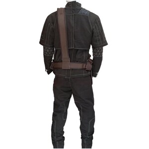 Op de afbeelding: Zwart tactisch kostuum met witte stikseldetails. Het kostuum bestaat uit een jasje met korte mouwen, een broek, en een bruine riem en schouderriem. De jas heeft geometrische patronen op de mouwen. Het kostuum is ontworpen voor functionaliteit en duurzaamheid.