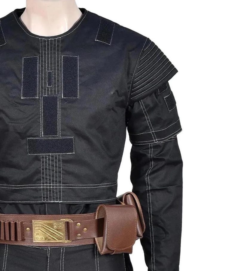 May include: A black long-sleeve tactical shirt with white contrast stitching, featuring rectangular hook-and-loop panels on the chest and ribbed shoulder detailing. A brown leather utility belt with a gold-toned buckle and pouch is worn.