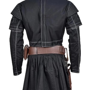May include: A black long-sleeved jacket with white topstitching, featuring ribbed shoulder panels and a central back seam. A brown leather utility belt with a side pouch and ammunition loops is worn over a black pleated skirt with a side holster.