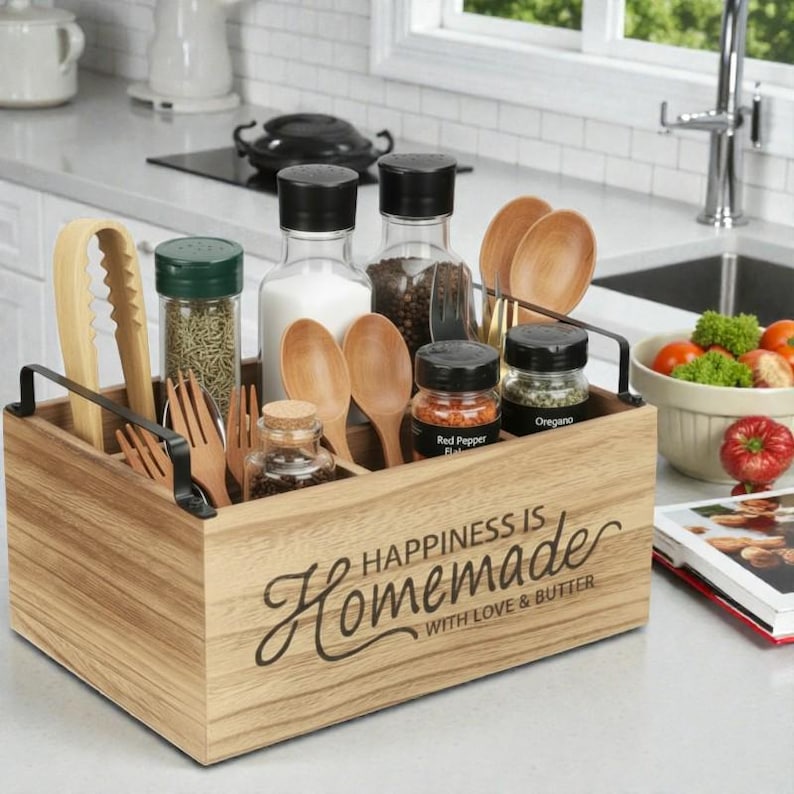 K&ouml;nnte beinhalten: Holz-K&uuml;chenutensilien- und Gew&uuml;rz-Organizer mit schwarzen Metallgriffen. Der Organizer enth&auml;lt Holzl&ouml;ffel, Gabeln, Zangen und Gew&uuml;rzgl&auml;ser. Auf der Vorderseite steht der Text "Happiness is Homemade with Love & Butter."