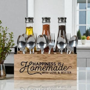 K&ouml;nnte beinhalten: Ein h&ouml;lzerner Utensilienhalter mit dem Text "Happiness is Homemade with Love & Butter". Der Halter enth&auml;lt Edelstahl-L&ouml;ffel und -Gabeln sowie drei Glasflaschen mit silbernen Deckeln. Die Flaschen enthalten &Ouml;l, Gew&uuml;rze und Pfeffer.