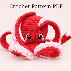 Puede incluir: Un pulpo de ganchillo rojo hecho a mano con detalles en blanco y rosa en sus tentáculos. El pulpo tiene ojos negros y una boca sonriente. El texto "Crochet Pattern PDF" está en la parte superior de la imagen.