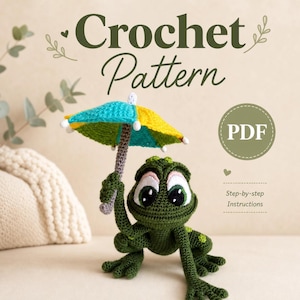 Könnte beinhalten: Ein Häkelmuster zeigt einen grünen Frosch, der einen bunten Regenschirm hält. Der Regenschirm ist gelb, blau und grün. Das Bild enthält den Text "Crochet Pattern" und "PDF".