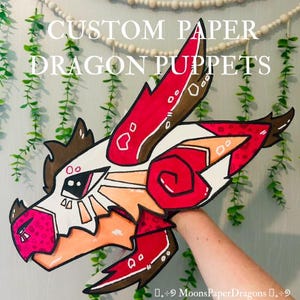 Può includere: Un burattino di drago di carta personalizzato in rosso, bianco, marrone e arancione. La testa del drago è tenuta da una mano. Il testo "CUSTOM PAPER DRAGON PUPPETS" è nella parte superiore dell'immagine.