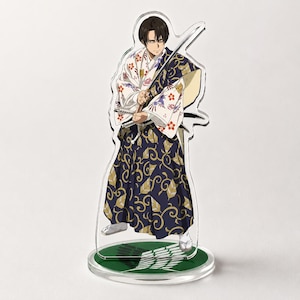 Könnte beinhalten: Klare Acrylfigur eines Charakters in einem traditionellen japanischen Kimono. Der Kimono ist weiß mit floralen Mustern und einem marineblauen Rock mit goldenen Wirbeln. Die Figur hält ein Schwert und steht auf einem grünen Sockel.