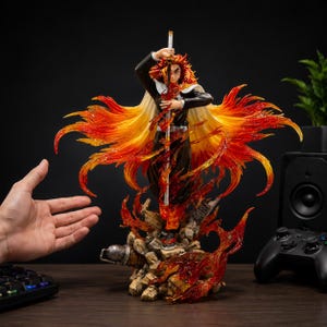 Könnte beinhalten: Eine detaillierte Anime-Charakterfigur eines Kriegers mit stacheligem gelb-rotem Haar, schwarzer Uniform und weißem Umhang. Die Figur hält ein Schwert vertikal und ist von durchscheinenden orangefarbenen und roten Flammeneffekten umgeben.