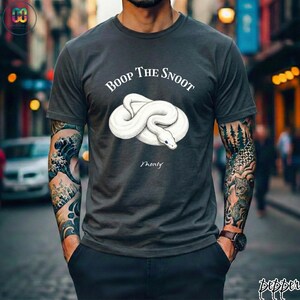 May include: Dark gray t-shirt featuring a white snake illustration with the text "Boop The Snoot" above and "Monty" below. The shirt is a crew neck style.