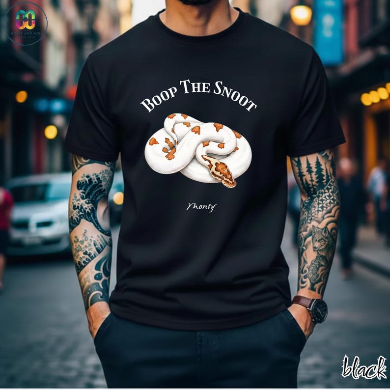 May include: Black t-shirt featuring a white and brown snake graphic with the text "Boop The Snoot" above the snake and the name "Monty" below. The word "black" is written in the bottom right corner.