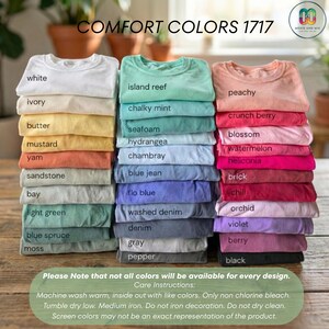 May include: Stacks of Comfort Colors 1717 t-shirts in various colors, including white, ivory, and peachy. The image displays a range of hues from light green to black, with the names of each color printed below. Care instructions are also included.