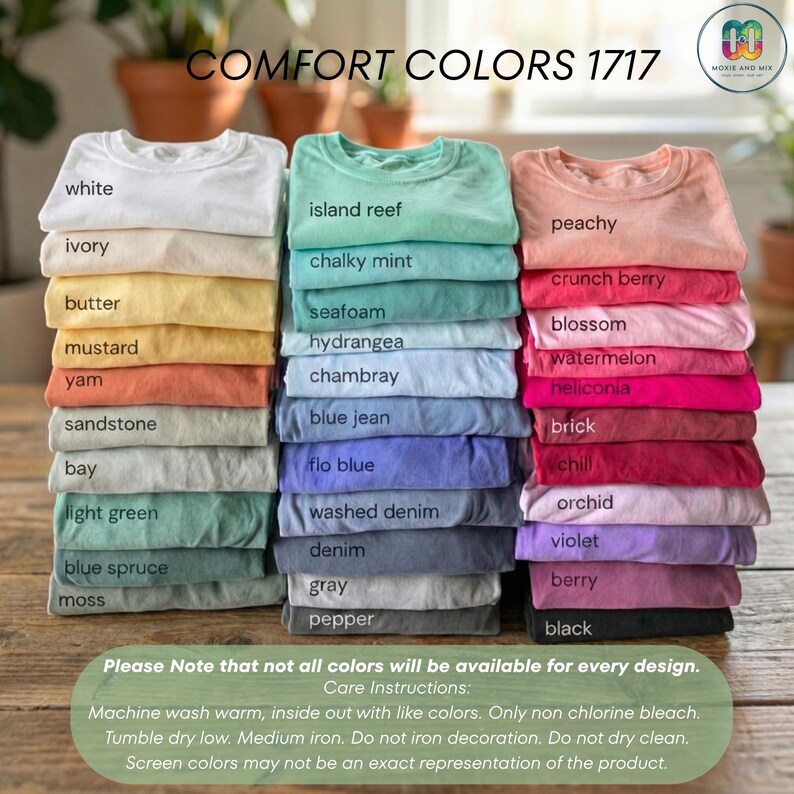 May include: Stacks of Comfort Colors 1717 t-shirts in various colors, including white, ivory, and peachy. The image displays a range of hues from light green to black, with the names of each color printed below. Care instructions are also included.
