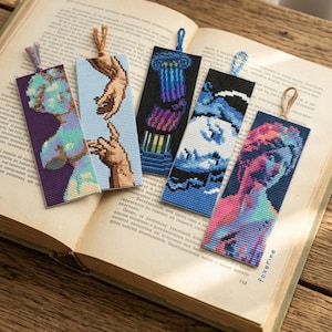 May include: Five rectangular cross-stitched bookmarks featuring diverse designs including a classical bust, reaching hands, a column, a swirling wave, and a colourful portrait, each topped with a small fabric loop for hanging.