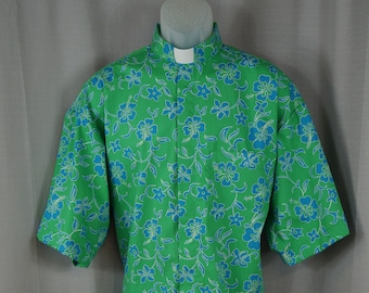 Camisa clerical CAMP, estampado tropical de hibisco azul sobre fondo verde. 100% algodón. Seleccione la talla. Confeccionada bajo pedido. Seleccione la opción TAB o Fullband. Estilo sin meter por dentro del pantalón.