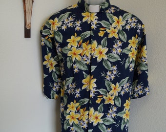 Camisa clerical CAMP con flores tropicales amarillas sobre fondo azul. Hecha a medida. Talla a elegir. Cuello a elegir. Listo para usar con TAB o banda completa. Estilo por fuera.