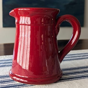May include: A set of three ceramic mugs with a speckled, matte finish. The mugs are in shades of cream, light gray, and dark gray. Each mug has a simple, minimalist design and a rounded handle.