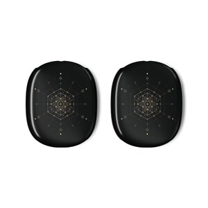May include: Two black, oval objects with a glossy finish. Each has a gold geometric design at the centre, surrounded by lines and dots. The symmetrical design is intricate, set against the dark background. The objects are likely accessories.
