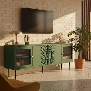 May include: A green mid-century modern style TV console with a carved leaf design on the center doors. The console has glass-fronted side cabinets and sits on black legs. A flat-screen TV is mounted above it.