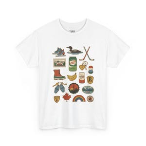May include: White t-shirt featuring a collection of colorful Canadian-themed illustrations. The design includes a loon, hockey sticks, a maple leaf, and other iconic symbols. The shirt is made of a soft, comfortable material.