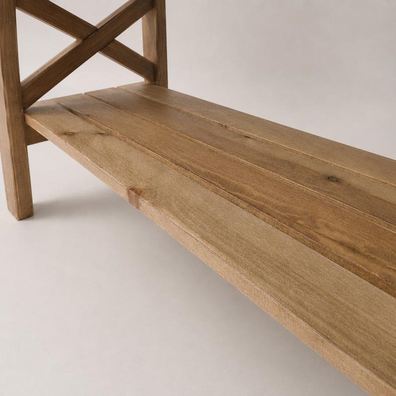 K&ouml;nnte beinhalten: Ein hellbrauner Holzkonsolentisch mit einer flachen, rechteckigen Oberfl&auml;che aus drei parallelen Brettern und einer seitlichen St&uuml;tzstruktur mit einem markanten X-f&ouml;rmigen Kreuzstreben-Design, das eine nat&uuml;rliche Holzmaserung aufweist.