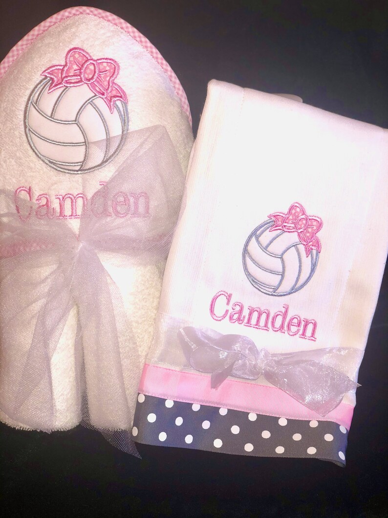 May include: White towel set with pink and black polka dot trim. The towels feature an embroidered volleyball with a pink bow and the name "Camden".