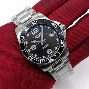 Könnte beinhalten: Eine Longines HydroConquest Automatikuhr aus Edelstahl mit schwarzem Zifferblatt, einer einseitig drehbaren Lünette mit weißen Ziffern und einem Datumsfenster auf der Drei-Uhr-Position. Die Uhr hat ein silberfarbenes Gliederarmband.