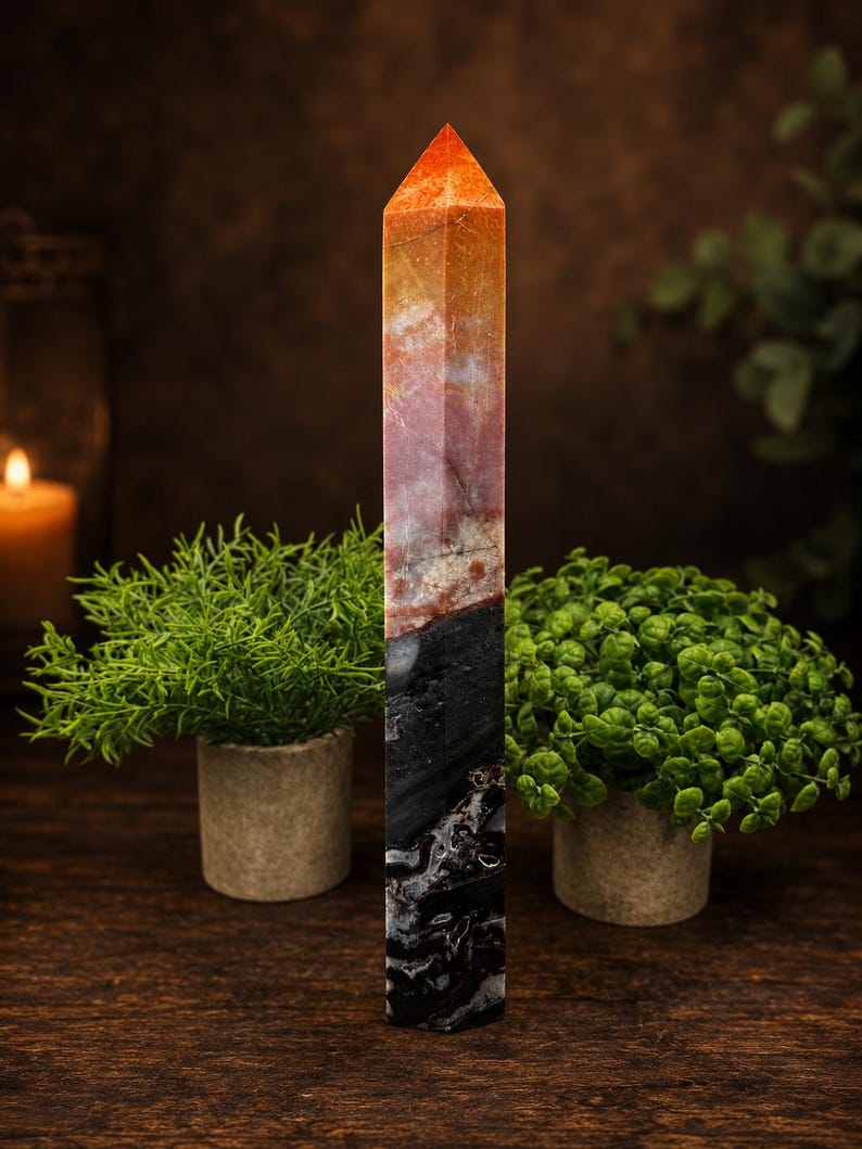 May include: A tall, hexagonal crystal tower featuring a distinct color gradient. The top section is a vibrant orange and red, transitioning into a dark, opaque black base with white veining throughout the stone's polished, smooth surface.