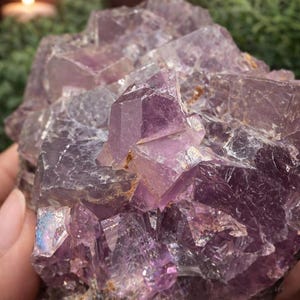Peut inclure: Gros plan sur un amas de cristaux d'am&eacute;thyste, pr&eacute;sentant diverses nuances de violet. Les cristaux pr&eacute;sentent des formes g&eacute;om&eacute;triques nettes, refl&eacute;tant la lumi&egrave;re et cr&eacute;ant un effet scintillant. La formation min&eacute;rale naturelle est tenue dans une main.