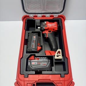 Puede incluir: Un kit de atornillador de impacto Milwaukee FUEL rojo y negro en una maleta rígida roja. El kit incluye el atornillador de impacto, dos baterías M18 REDLITHIUM XC 5.0 y un cargador. La maleta tiene una tapa transparente.