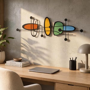 May include: A horizontal wall art piece featuring a black metal frame with interconnected lines and circles. It includes four distinct colored shapes: an orange oval, a yellow vertical oval, a green irregular form, and a blue rounded rectangle.