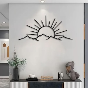 Pu&ograve; includere: Arte da parete in metallo nero raffigurante un'alba su una catena montuosa. Il sole ha linee radianti e le montagne hanno una silhouette frastagliata. L'opera d'arte &egrave; montata su una parete bianca, creando un contrasto. Il marchio "ChenDuo" &egrave; visibile.