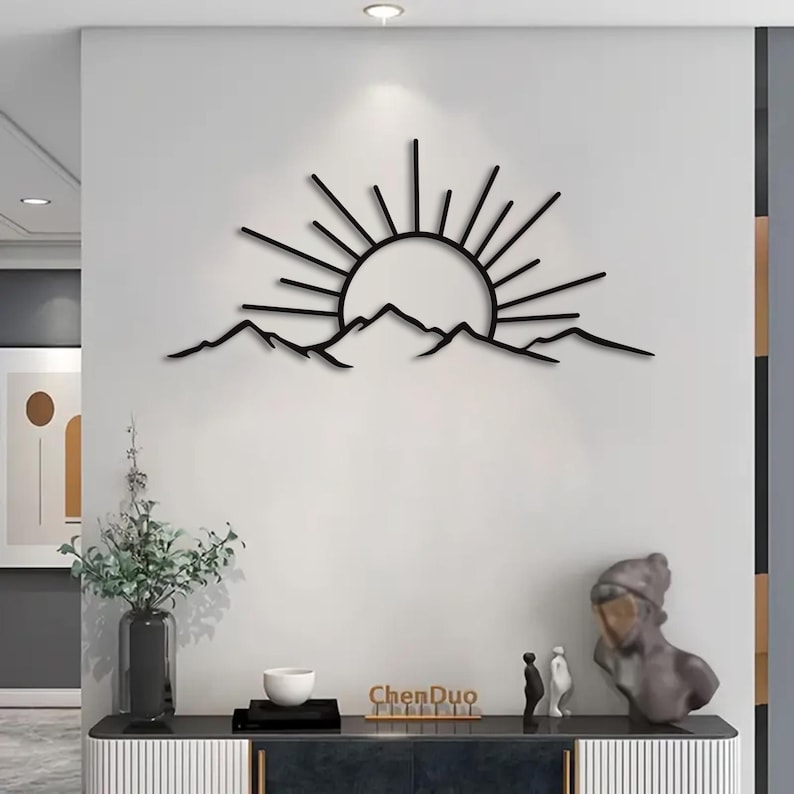 Pu&ograve; includere: Arte da parete in metallo nero raffigurante un'alba su una catena montuosa. Il sole ha linee radianti e le montagne hanno una silhouette frastagliata. L'opera d'arte &egrave; montata su una parete bianca, creando un contrasto. Il marchio "ChenDuo" &egrave; visibile.