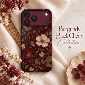 May include: A burgundy smartphone case featuring a botanical print of dark red and pale pink flowers with green leaves. The text Burgundy Black Cherry Collection is printed to the right of the case in a dark serif and script font.